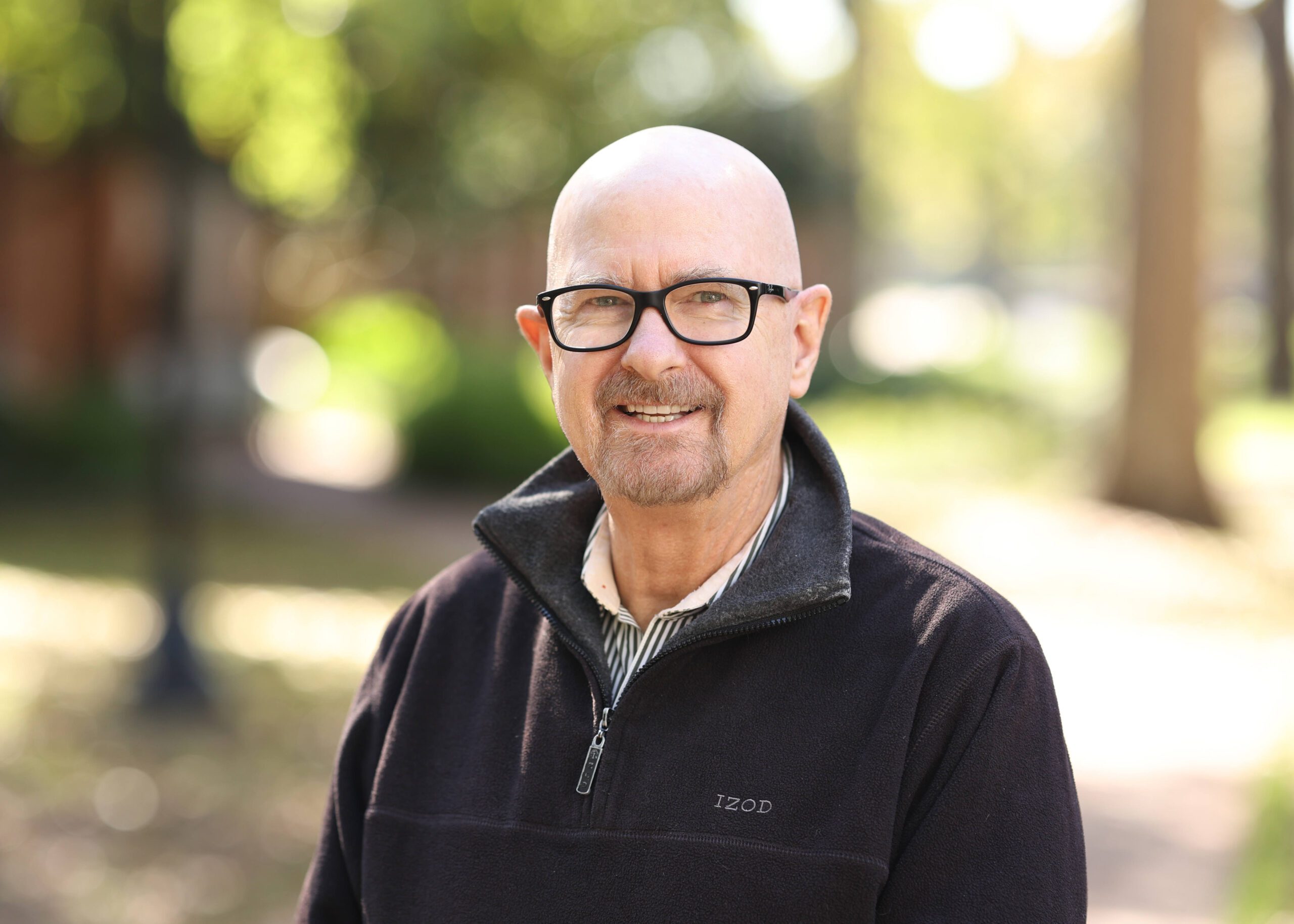 A man wearing glasses and smiling with a jacket on.