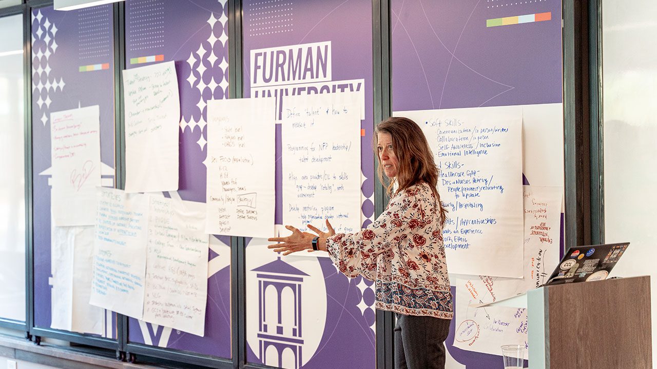A woman speaks to a group next to a podium