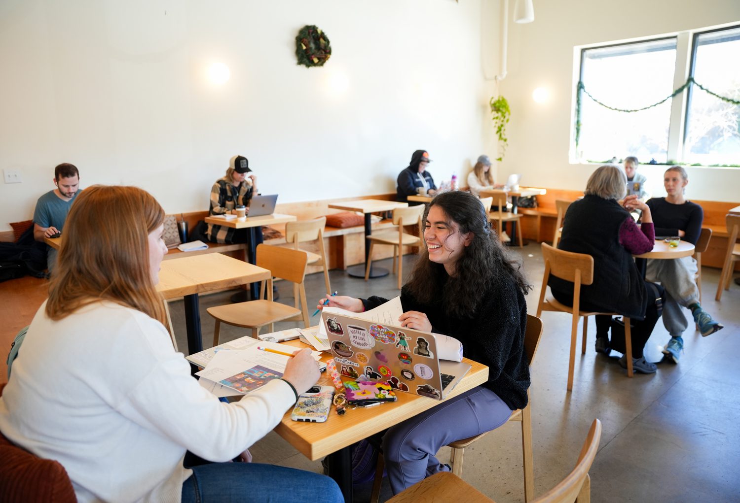 Sara Harbin ’28, left, and Nina Mahintorabi ’28, study at Other Lands in Greenville, which is owned and operated by Mel Wilcox ’15. Photo by Nathan Gray, Furman University.