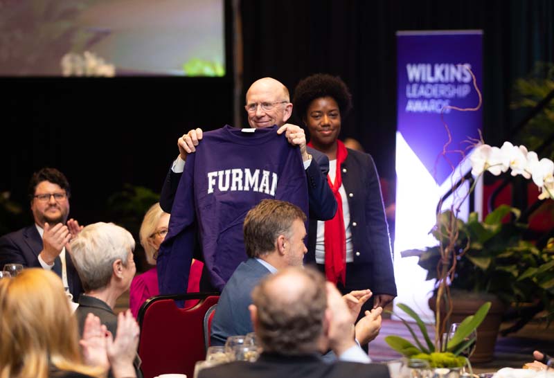 Shekinah Lightner, an Advance Team member, presenting a Furman sweatshirt to David Wilkins