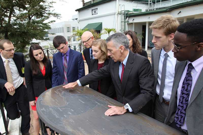 Ambassador Phillip Goldberg shows students the map outside of the embassy, which looks out over Manila Bay.